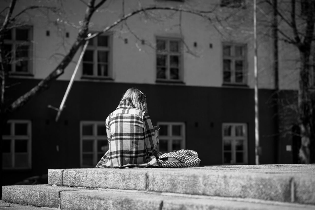 Tyttö istuu selkä kameraan päin kiviportailla.